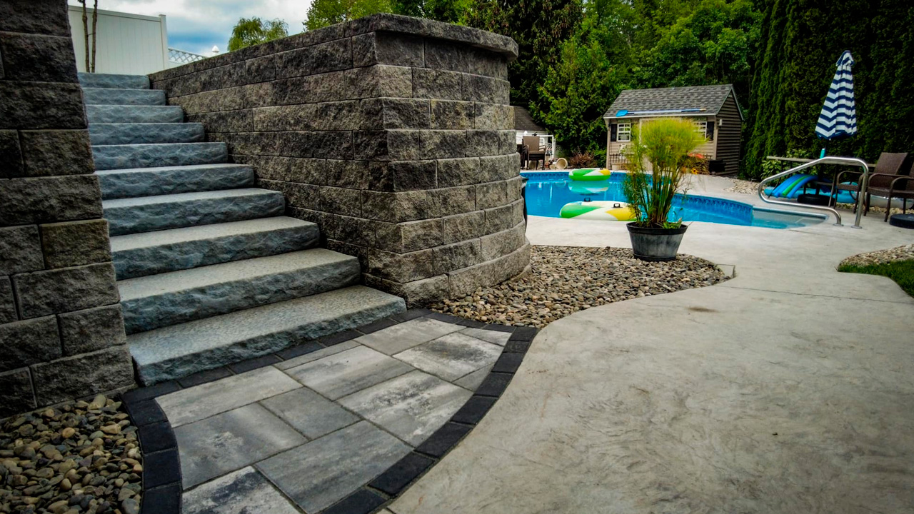 Back yard Retaining wall with steps next to a pool installed by blackdiamonddesign Landscaping